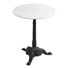 a white marble top table with black metal base and an ornate design on the legs