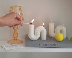 a person lighting a candle on top of a book with the word joy spelled out