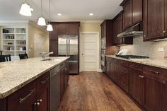 an empty kitchen with wood floors and stainless steel appliances in the center, along with wooden cabinets