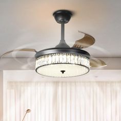 a ceiling fan that is hanging from the ceiling in a room with white walls and curtains