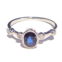 This Darling ring has a Natural, faceted, oval cut, 1.00ctw Genuine Blue Sapphire, (mined, not lab created, with four tiny, 1.5mm, faceted, Genuine Diamonds on the band. The Sapphire is SI color, and 7.40mm North to South. The hight above the finger is 4.85mm, shank width is 1.30mm, and gram weight is 1.8g. The .07ctw Diamonds are round, with I color, and SI Clarity. The ring is .925 Sterling Silver, in a size 7, resizable by your local silver smith or jeweler, if need be. This little Beauty wou Oval Sapphire Ring With Rose Cut Diamonds For Promise, Oval Sapphire Ring With Rose Cut Diamonds, Oval Sapphire Diamond Ring With Rose Cut Diamonds, Oval Diamond Birthstone Ring With Bezel Setting, Blue Oval Birthstone Ring With Diamond Accents, Oval Sapphire Promise Ring With Ethical Diamonds, Oval Sapphire Diamond Ring With Bezel Setting, Oval Sapphire Ring With Bezel Setting, Oval Birthstone Ring With Rose Cut Diamonds For Promise