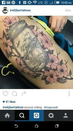 a woman's thigh with flowers and a mason jar tattoo on her leg,