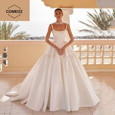 a woman in a white wedding dress standing on a balcony with her hands on her hips