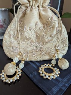 Handmade light beige silk potli bag with gold-white beads work, exclusively presented by Roopayan Boutique. Pearl round tussles give a stunning look. Color - light beige Fabric- Silk Gold Bohemian Shoulder Bag For Wedding, Bohemian Gold Potli Bag For Festive Season, Traditional Pearl Embroidered Potli Bag For Formal Occasions, Bohemian Gold Potli Bag For Wedding, Formal Gold Pouch Potli Bag, Traditional Formal Potli Bag With Pearl Embroidery, Formal Gold Potli Pouch Bag, Traditional Pearl Embroidery Potli Bag For Formal Occasions, Elegant Handmade Potli Bag For Diwali