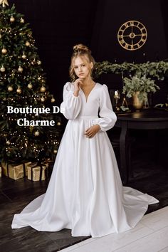 a woman in a white dress standing next to a christmas tree with the words boutique de charme on it