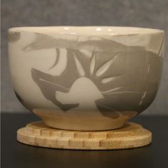 a white and gray bowl sitting on top of a wooden stand