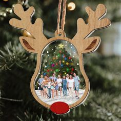 a christmas ornament with a family photo hanging from it's side in front of a christmas tree