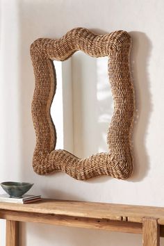 a wooden table with a mirror on top of it next to a wall mounted shelf