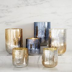 five gold and silver vases sitting on top of a white counter