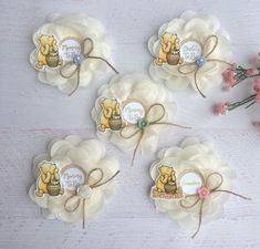 four winnie the pooh paper flowers on a white surface with pink flowers in the background