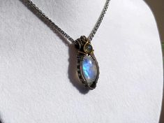 Elevate your style with this stunning handcrafted wire wrapped necklace featuring a shimmering blue Moonstone and a petite green Labradorite. The intricate wire wrapping is crafted using German silver and brass wire, adding a touch of elegance to the design. Measuring approximately 2x4 cm, this necklace hangs beautifully on a silver snake chain, creating a chic and timeless look. It makes a perfect gift for Mother's Day or any special occasion. Ready to ship with free shipping included. Materials: - Blue Moonstone - Green Labradorite - German Silver Wire - Brass Wire - Silver Snake Chain 45 cm  Dimensions: Pendant Size: Approximately 2x4 cm Daily Wear Necklace, Labradorite Gemstone Jewelry, Green Labradorite, Jewelry Elegant, Wrapped Necklace, Wear Necklaces, Blue Moonstone, Silver Snake Chain, Wire Wrapped Necklace