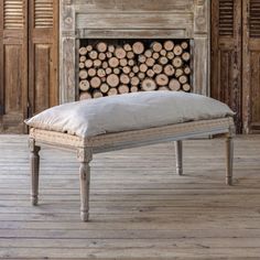 a bench sitting on top of a wooden floor in front of a firewood log