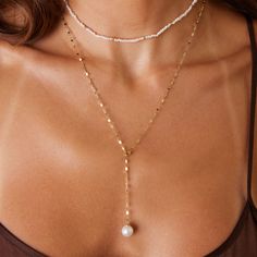 Whether you're dressing up for a special occasion or adding a touch of refinement to your everyday look, the Demure Pearl Drop Chain Lariat is the perfect choice for those who believe in the power of subtlety and grace. This lariat is as versatile as it is stunning. Perfect for layering with other pieces or wearing solo as a statement of understated elegance. It’s a piece that speaks volumes with its quiet elegance, designed to be worn and treasured for years to come. 

Link Size: 2mm (W)
Pearl: Luxury White Lariat Necklace As Gift, Pearl Dangle Necklace, Cheap Gold Lariat Necklaces, Luxury Dainty White Gold Lariat Necklace, Luxury White Gold Lariat Necklace With Delicate Chain, Elegant Single Strand Chain Necklace For Party, Elegant Beaded Chain Necklace, Elegant Formal Beaded Chain Necklace, Elegant Lariat Chain Necklace For Party