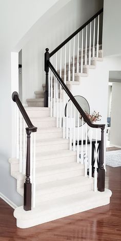 a white staircase with black railing and mirror on the top handrail in a home