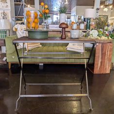 a green bench sitting inside of a store next to a table with oranges on it