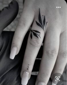 a black and white photo of a woman's hand with a leaf tattoo on it