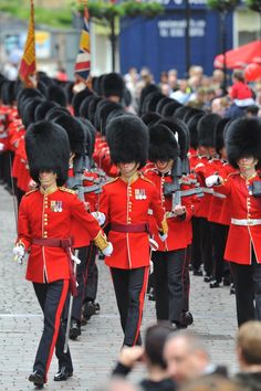 a group of men in red uniforms marching down the street