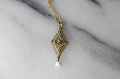 "Antique Edwardian era lavaliere charm made of 14k gold. The charm has an openwork design with stamped details including small flowers at each corner. The center of the charm gold a small diamond in a buttercup setting. At the bottom hangs a natural looking pearl. Era: Edwardian Markings: 14k Material: 14k gold, diamond, pearl Measurements: 32.5mm x 12.8mm. Comes with a new 18\" gold filled chain. Condition: Excellent antique condition with minor surface wear from age Shipping is free in the Uni Ornate Yellow Gold Jewelry With Rose Cut Diamonds, Ornate Gold Jewelry With Rose Cut Diamonds, Elegant Yellow Gold Jewelry With Vintage Charm, Elegant Antique Gold Flower Pendant Jewelry, Elegant White Gold Necklace With Vintage Charm, Elegant White Gold Jewelry With Vintage Charm, Ornate 14k Gold Antique Gold Jewelry, Vintage 14k Gold Flower Pendant Jewelry, Ornate 14k Gold Wedding Necklace