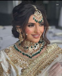 a woman in a bridal outfit with jewelry on her head and necklaces around her neck