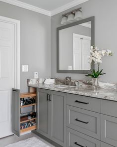 a bathroom with gray cabinets and marble counter tops