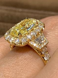 a fancy yellow diamond ring on someone's finger