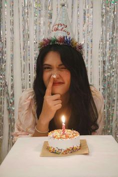 a woman sitting at a table in front of a birthday cake with a lit candle