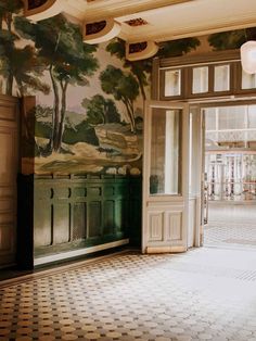 an empty room with a mural on the wall and doors leading to another room that has a tiled floor