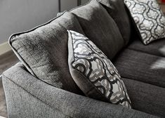 a gray couch with two pillows on it's back and one pillow in the middle