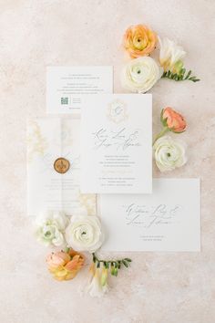 the wedding stationery is laid out on top of each other, with flowers in between them