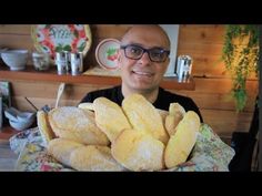 a man sitting at a table with some bread in front of him and smiling for the camera