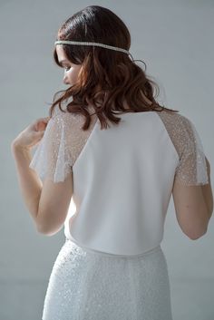 This crop top features a double bias cut satin bodice (no bust darts!) and wide, sparkly beaded raglan sleeves and a crew neck. We recommend strapless bra underneath this wedding crop top. Only available in the shown IVORY color. Please be aware that your veil or other items can stick to this top's sleeves due to sequins, it can also stick together a little bit at times, and you may lose some beads or sequins while wearing it - it is perfectly normal and won't be noticeable in grand scheme of th Elegant Cropped Crop Top For Wedding, Elegant Embellished Wedding Crop Top, Elegant White Crop Top For Wedding, Elegant Cropped Crop Top With Sheer Sleeves, White Sheer Sleeve Wedding Top, White Sheer Sleeves Top For Wedding, Elegant Wedding Crop Top, White Sheer Sleeve Tops For Wedding, Fitted Sequin Top For Wedding