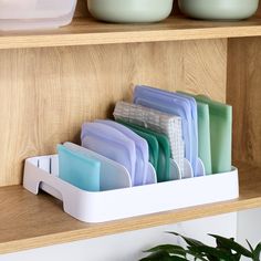 there are many plates and cups in the holder on the shelf next to each other