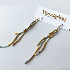 a pair of earrings with beads hanging from it's earwires on top of a card