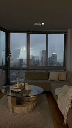 a living room filled with furniture and large windows overlooking the cityscape in the distance