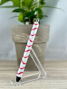 a red and white striped pen sitting on top of a table next to a potted plant