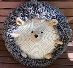 a crocheted hedge rug hanging on the side of a wooden wall with a stuffed animal