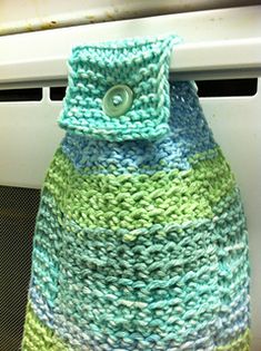 a green and blue knitted bag sitting on top of an oven door sill