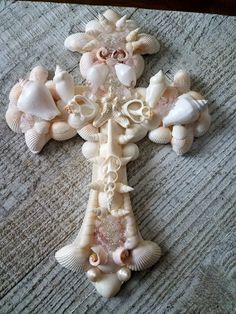 a cross made out of seashells and shells on a rug with a gray background