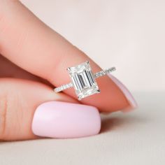 a woman's hand holding an engagement ring with a large emerald stone on it