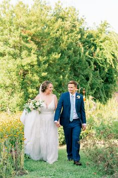 a bride and groom walking through the grass