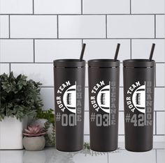 three black tumblers sitting on top of a counter