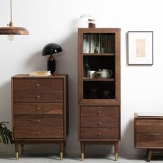 an empty room with two wooden drawers and a lamp on the side table next to it