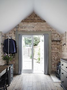 an open door leading to a bedroom with brick walls and wooden flooring in the room