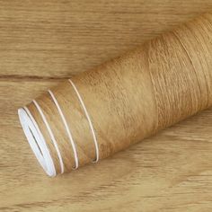 a roll of brown string on top of a wooden table next to a white strip