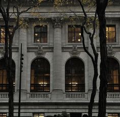 an old building is lit up at night with the lights on and trees in front