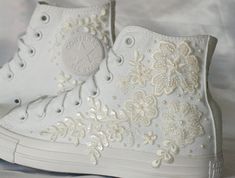 a pair of white high top sneakers with flowers and pearls embellishment on them