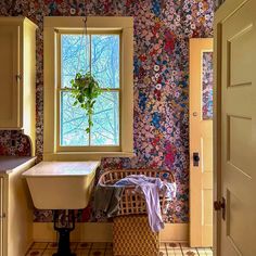 a bathroom with floral wallpaper and a sink in the corner next to a window