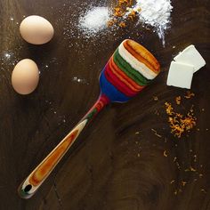 a wooden table topped with eggs, sugar and an egg spatula on top of it