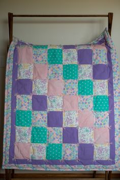 a purple and green patchwork quilt on a bed