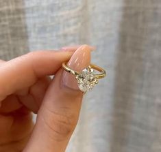 a woman's hand holding an engagement ring with two diamonds on it, in front of a curtain